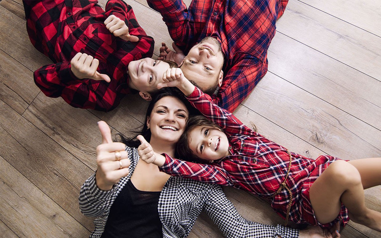 Happy family laying on hardwood | Xtreme Carpet Care